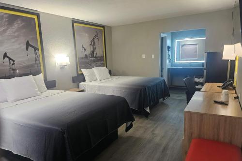 a hotel room with two beds and a desk at Super 8 by Wyndham Hobbs in Hobbs