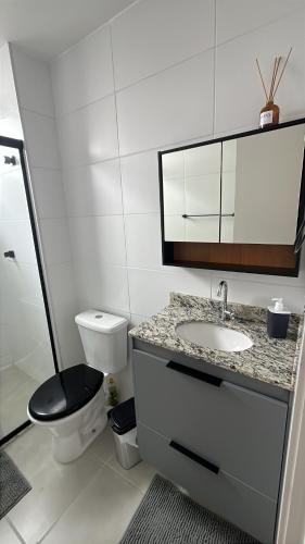 a white bathroom with a toilet and a sink at Doce Lar 2 in Pouso Alegre