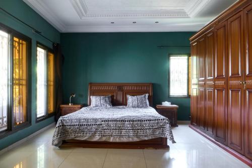 una camera da letto con un letto con pareti e finestre verdi di LA Maison Sur Le Fleuve a Bamako