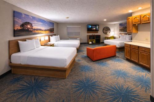 a hotel room with two beds and an orange chair at Days Inn by Wyndham Sturgis SOUTHDAKOTA in Sturgis