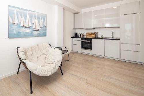 a living room with a chair and a kitchen at Ostsee Suite 2 - Penthouse in Niendorf