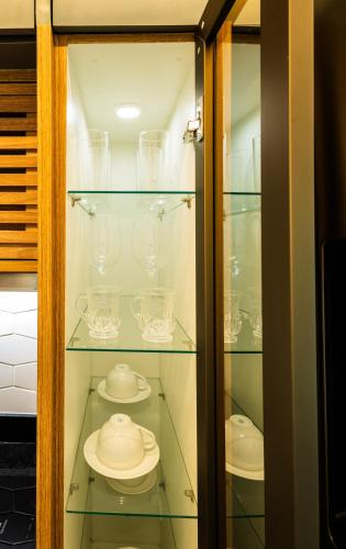 a glass cabinet with glasses and dishes in it at Art studio open space in Água Boa