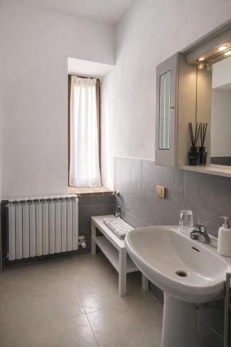 a white bathroom with a sink and a window at Residenza Il Castello Tre in CastellʼArquato