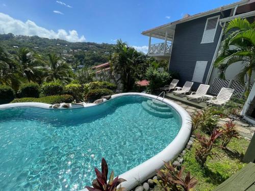a swimming pool in a yard with chairs and a house at Oasis Marigot Bay in Marigot