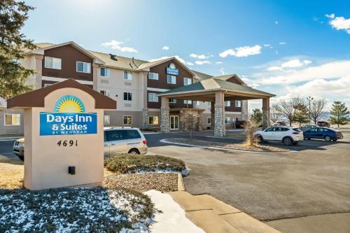 a sign in front of a building with a dogs inn and suites at Days Inn & Suites by Wyndham Castle Rock in Castle Rock