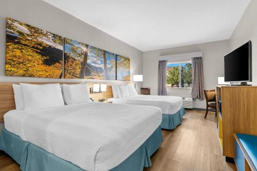 a hotel room with two beds and a flat screen tv at Days Inn & Suites by Wyndham Castle Rock in Castle Rock