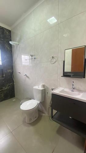 a bathroom with a toilet and a sink and a mirror at Casa da Clau in Olímpia