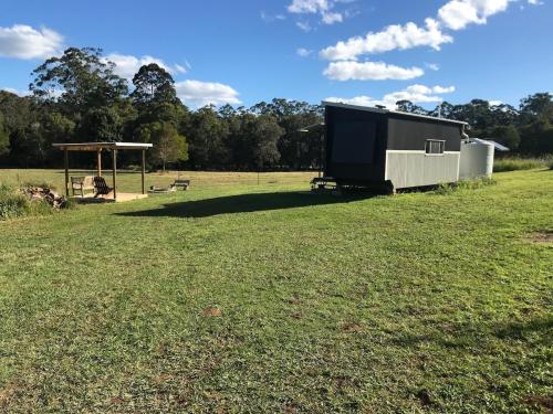 a large field with a shed and a playground at Bee Farm Off-Grid Tiny Home Stay in Tamaree