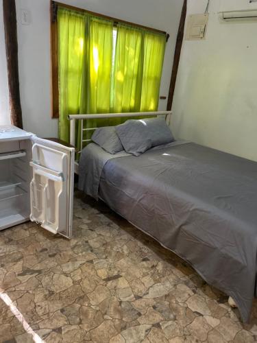 a bedroom with a bed and a window with green curtains at Cabaña-estudio selvatica in Utila