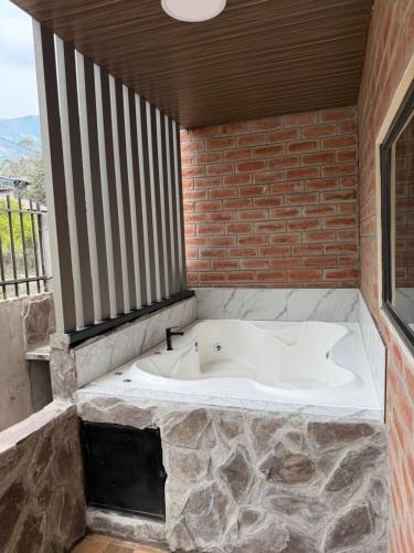 a bath tub in a room with a brick wall at Relajate en una TinyHouse privada en Baños de Agua Santa con Jacuzzi y vistas increíbles in Baños