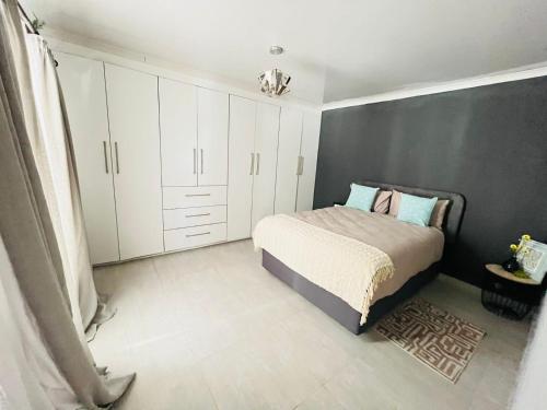a bedroom with a bed and white cabinets at Legae la rena in Polokwane