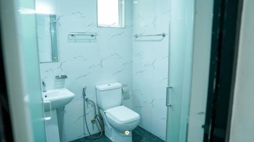 a white bathroom with a toilet and a sink at The Duchess Hotel in Matara