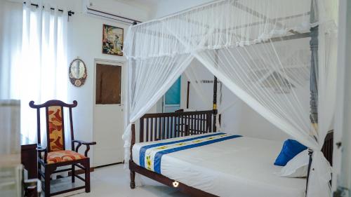 a bedroom with a canopy bed and a chair at The Duchess Hotel in Matara