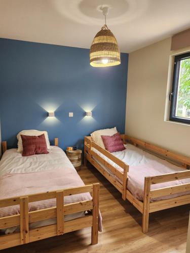 Forest Home في Bazoches-sur-le-Betz: سريران في غرفة ذات جدران زرقاء