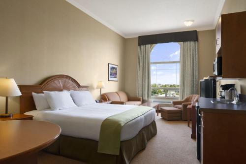 a hotel room with a bed and a large window at Super 8 by Wyndham Fort St. John BC in Fort Saint John