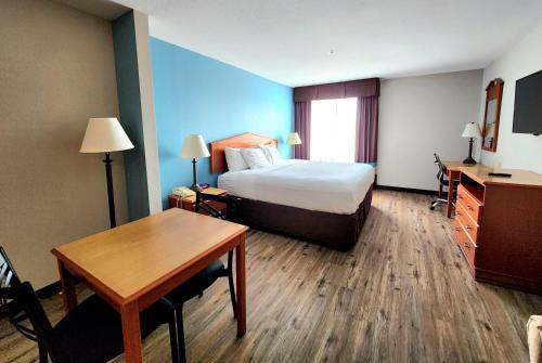 a hotel room with a bed and a desk and a table at Days Inn & Suites by Wyndham Thibodaux in Thibodaux