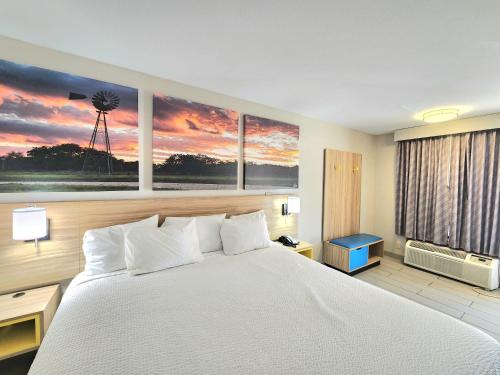 a bedroom with a large bed and a windmill painting at Days Inn by Wyndham McAllen in McAllen