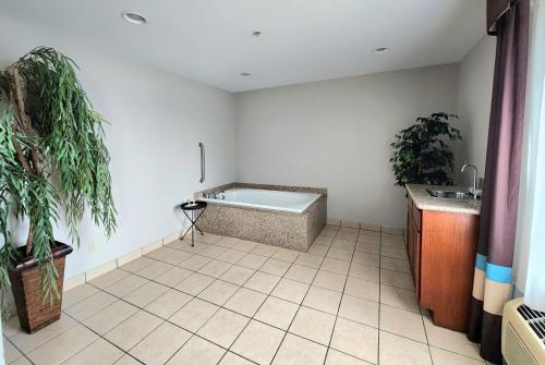 a bathroom with a bath tub and two plants at Days Inn & Suites by Wyndham Thibodaux in Thibodaux