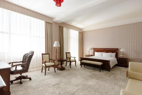 a hotel room with a bed and a table and chairs at Ramada Plaza by Wyndham Gence in Ganja