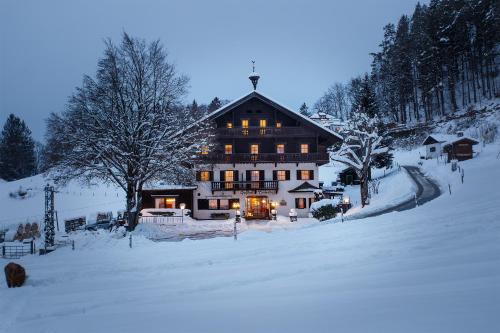 a large house in the snow with lights on at Berghotel Hinterduxerhof in Sparchen