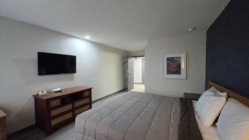 a bedroom with a bed and a tv on the wall at Roosevelt Inn at Roosevelt Blvd, Philadelphia, PA in Philadelphia