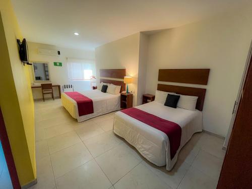 a hotel room with two beds and a television at Casa de la iaia Hotel in Orizaba