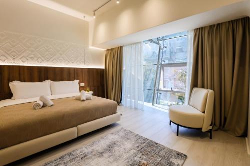 a bedroom with a bed and a chair and a window at A Gallery Hotel in Shkodër