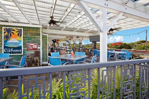 a restaurant with blue chairs and tables on a balcony at Kiahuna Plantation Resort Kauai by OUTRIGGER in Koloa