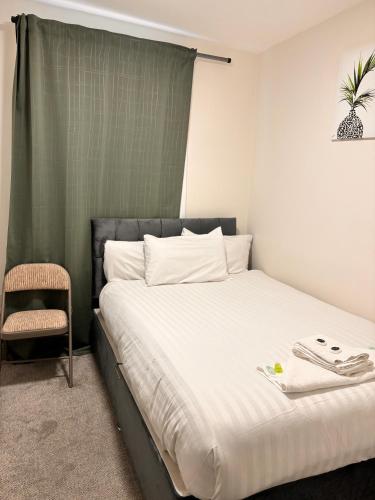 a bedroom with a bed with a chair and a plant on the wall at 18 Budget Inn in London