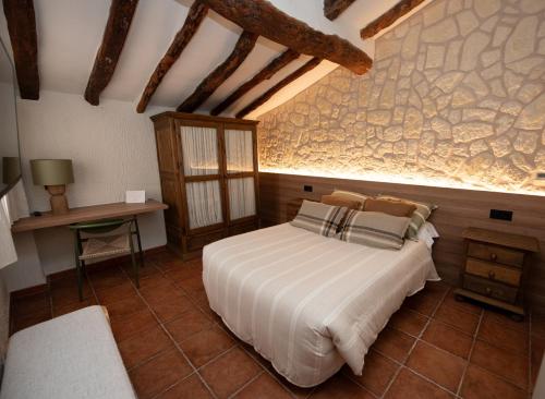 a bedroom with a bed and a stone wall at Hotel Caseta Nova in Castalla