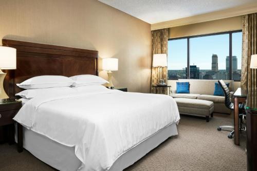 a bedroom with a large white bed and a couch at Memphis Riverline Hotel in Memphis
