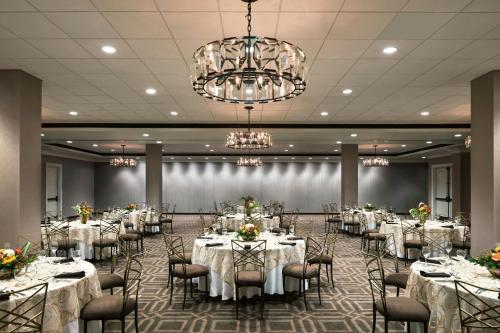 a banquet hall with white tables and chairs and a chandelier at Memphis Riverline Hotel in Memphis