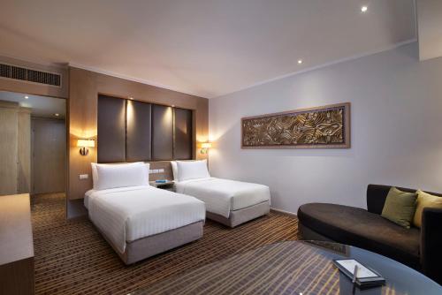 a hotel room with two beds and a couch at Amari Bangkok in Bangkok