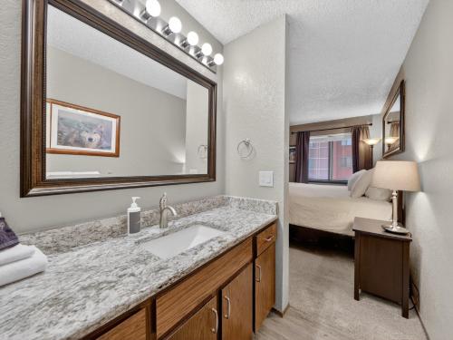 a bathroom with a sink and a mirror and a bed at Giant Steps 28 Ski in out in Brian Head
