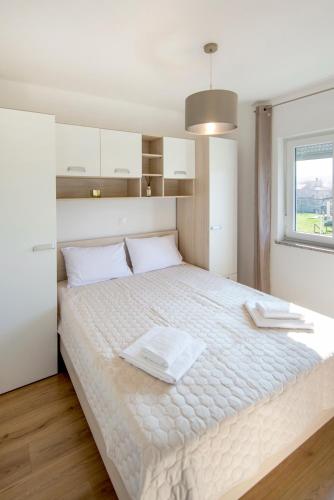 a bedroom with a large white bed with a window at Apartman Denis in Pula