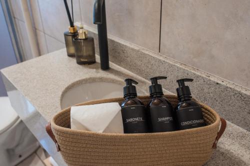 a basket with four hair products on a bathroom counter at Apartamento Brisa in Veranópolis
