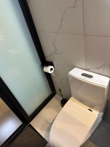 a white toilet in a bathroom with a roll of toilet paper at Bright 1BR Apartment Close to Everything in Kigali