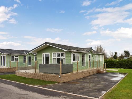 a green house with a large front yard at Bears Lodge in Cockermouth