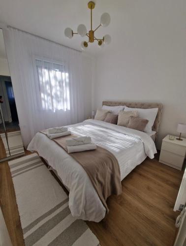 a white bedroom with a large bed with a chandelier at Yes Boss House Divcibare in Divčibare