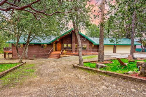 a log cabin with a green roof in the woods at Summit Cabin Stunning home Loaded with amenities in Oakhurst