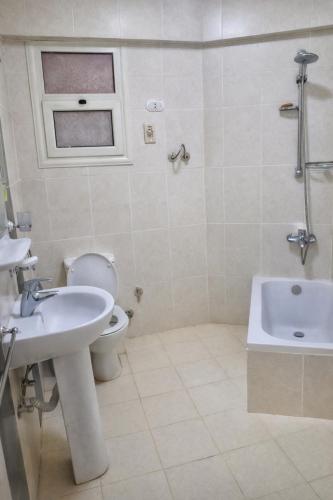 a bathroom with a sink and a toilet and a tub at Lazorde Bay Apartment in El Alamein