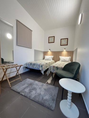 a room with two beds and a chair and a table at Granny House Madeira in Funchal