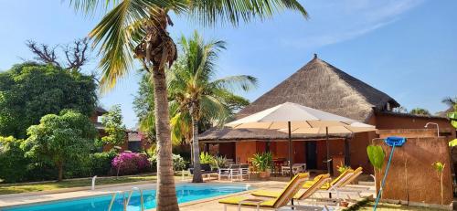 un resort con piscina attrezzata con sedie e ombrelloni di villa de standing a Nianing