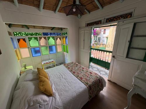 ein Schlafzimmer mit einem Bett in einem Zimmer mit Buntglasfenstern in der Unterkunft Hostal La Cestería Pueblito Boyacense in Duitama