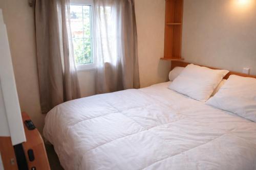a bedroom with a large white bed with a window at Mobil-home tout équipé Le Castellet les pins doux 2 in Le Castellet