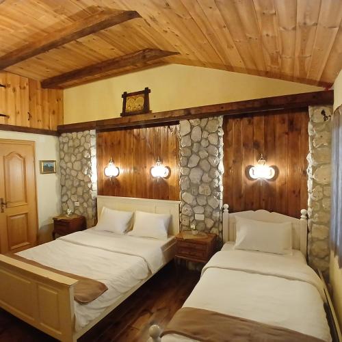 two beds in a room with wooden walls and wooden floors at Vila Merak in Gusinje