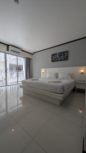 a white bedroom with a large bed and a large window at Issara Patong in Patong Beach