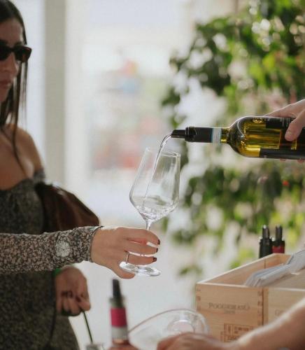 a woman pouring wine into a wine glass at Life House B&B in Follonica