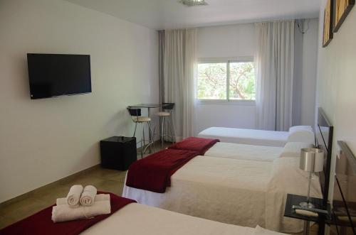 ein Hotelzimmer mit zwei Betten und einem Flachbildfernseher in der Unterkunft Hotel Oaky in Posadas