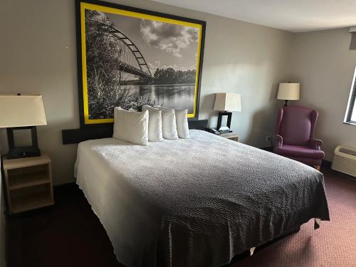 a hotel room with a bed with a painting on the wall at Super 8 by Wyndham Fort Scott in Fort Scott